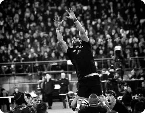 rugby player jumping high in the air to catch the ball during a lineout. The crowd in the background adds excitement and shows that this is an important moment in the game